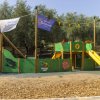 Parco giochi per bambini con scivolo e strutture verdi.