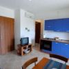 Una cucina blu con tavolo e sedie, TV su mobile e porta di legno.