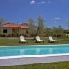 Una piscina azzurra con sedie a sdraio, casa sullo sfondo e cielo blu.