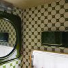 Interno con specchio tondo, pareti piastrellate verdi e bianche.