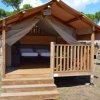 Tenda safari in legno con veranda e letti all'interno.