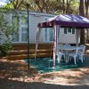 Una casa mobile con veranda e tavolo sotto un tendalino in un bosco.