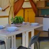 Interno di una tenda glamping con tavolo apparecchiato, sedie nere e angolo cottura.