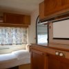 Camera con letto singolo e armadietti in legno, finestra con tende floreali.