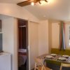 Interno di una casa mobile con cucina attrezzata, tavolo da pranzo e salottino verde.