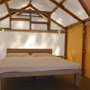 Tenda glamping con letto matrimoniale, illuminazione e struttura in legno.