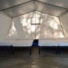 Interno di una tenda con quattro letti singoli su pavimento in legno.
