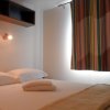 Camera con letto matrimoniale, mensola, tende a righe e lampade da parete.