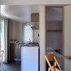 Interno compatto con cucina, tavolo apparecchiato e porta aperta verso una camera.