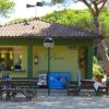 Un piccolo bar con tavoli all'aperto, circondato da alberi verdi sotto un tetto a spiovente.