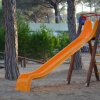 Uno scivolo arancione con scala in un parco giochi tra gli alberi.