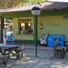 Bar all'aperto con tavoli di legno e distributore di gelati.