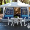 Una tenda blu con un gazebo bianco e un tavolo con sedie di plastica all'aperto.