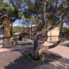 Edificio giallo con camino circondato da alberi, piazzale pavimentato e un'auto parcheggiata.