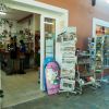 Ingresso di un negozio con giornali e cartoline esposte all'esterno.