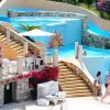 Piscina con scivoli, sedie a sdraio e persone che relax.