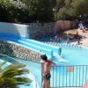 Un parco acquatico con scivoli d'acqua, piscine e visitatori che si divertono sotto il sole.