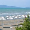 Una spiaggia sabbiosa con ombrelloni bianchi e il mare sullo sfondo.