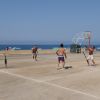 Quattro uomini giocano a pallavolo su un campo all'aperto vicino alla spiaggia.