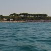 Spiaggia affollata con ombrelloni blu vista dal mare.
