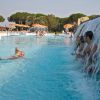 Una piscina con una cascata d'acqua e persone nuotando e giocando.
