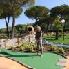 Donna gioca a minigolf in un parco verde.